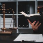 Advogado lendo livro com balança da justiça e martelo, para entender adiantamento de RPV.