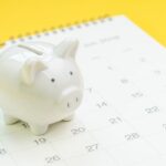 Cofrinho em cima de calendário, representando o adiamento de RPV Federal