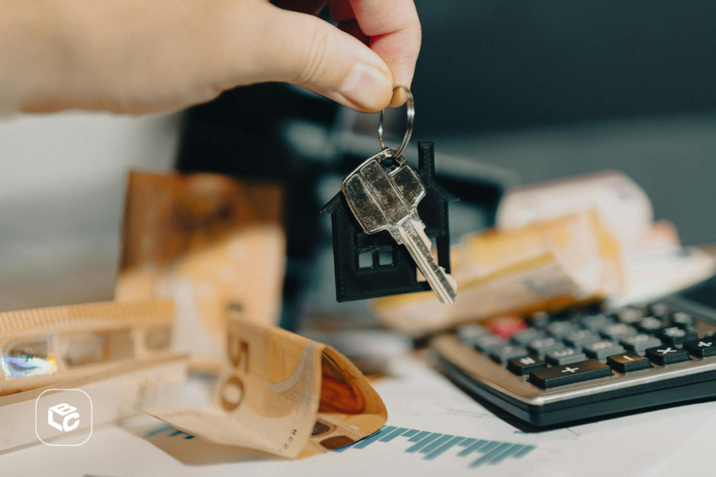 Chave de casa com pingente de casa sobre dinheiro e calculadora