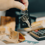 Chave de casa com pingente de casa sobre dinheiro e calculadora