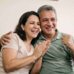Casal sorrindo e comemorando, com homem abraçando mulher.