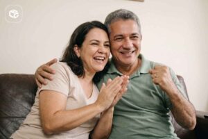 Casal sorrindo e comemorando, com homem abraçando mulher.